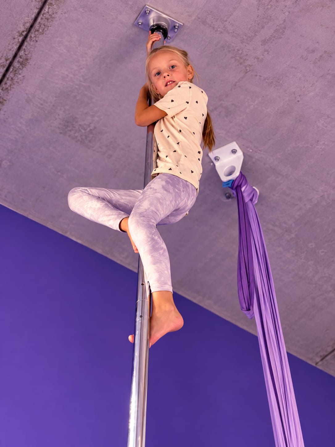 Kind klettert an der Stange im Aerial Sportstudio
